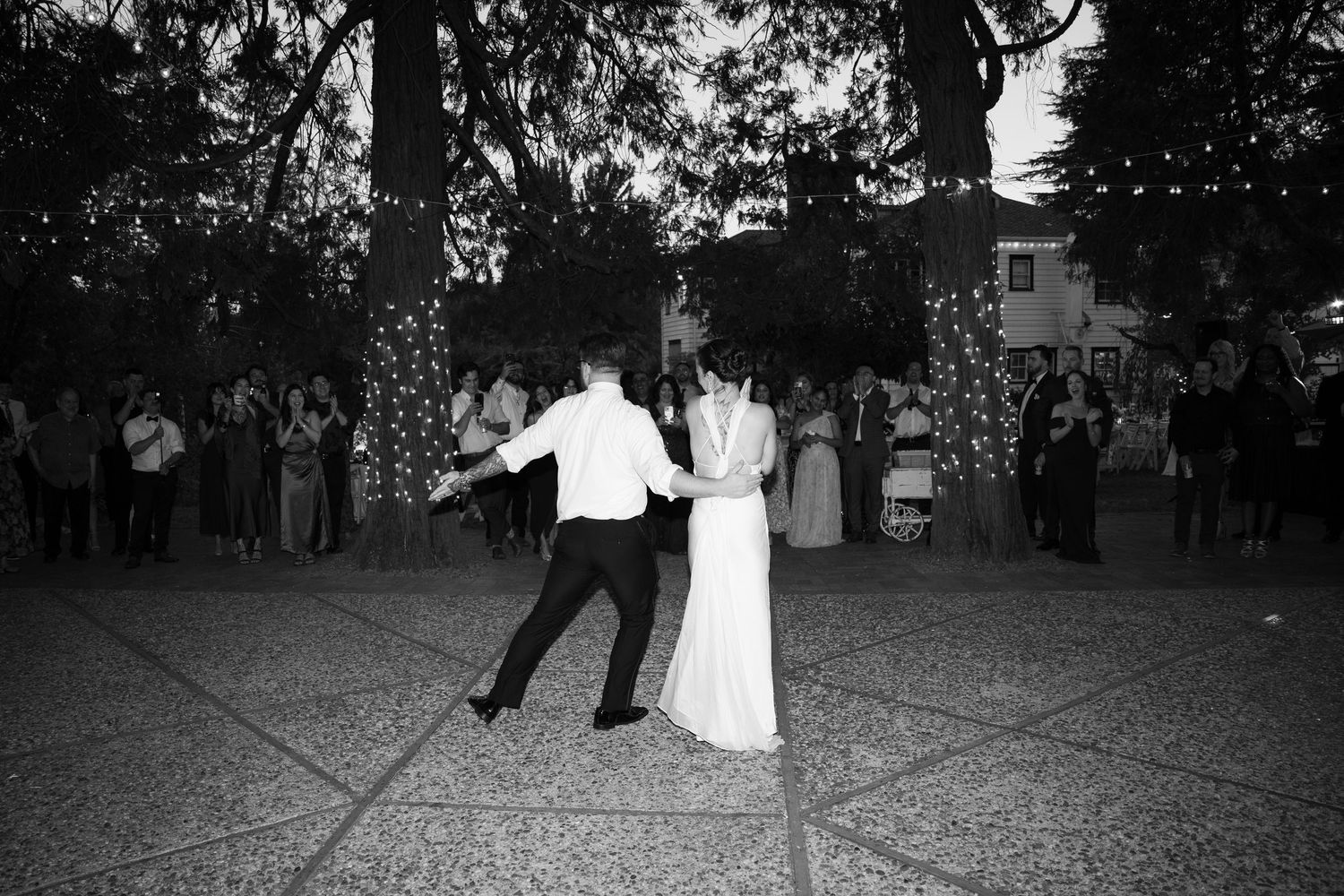 A couple dances energetically at their black and white outdoor wedding reception.