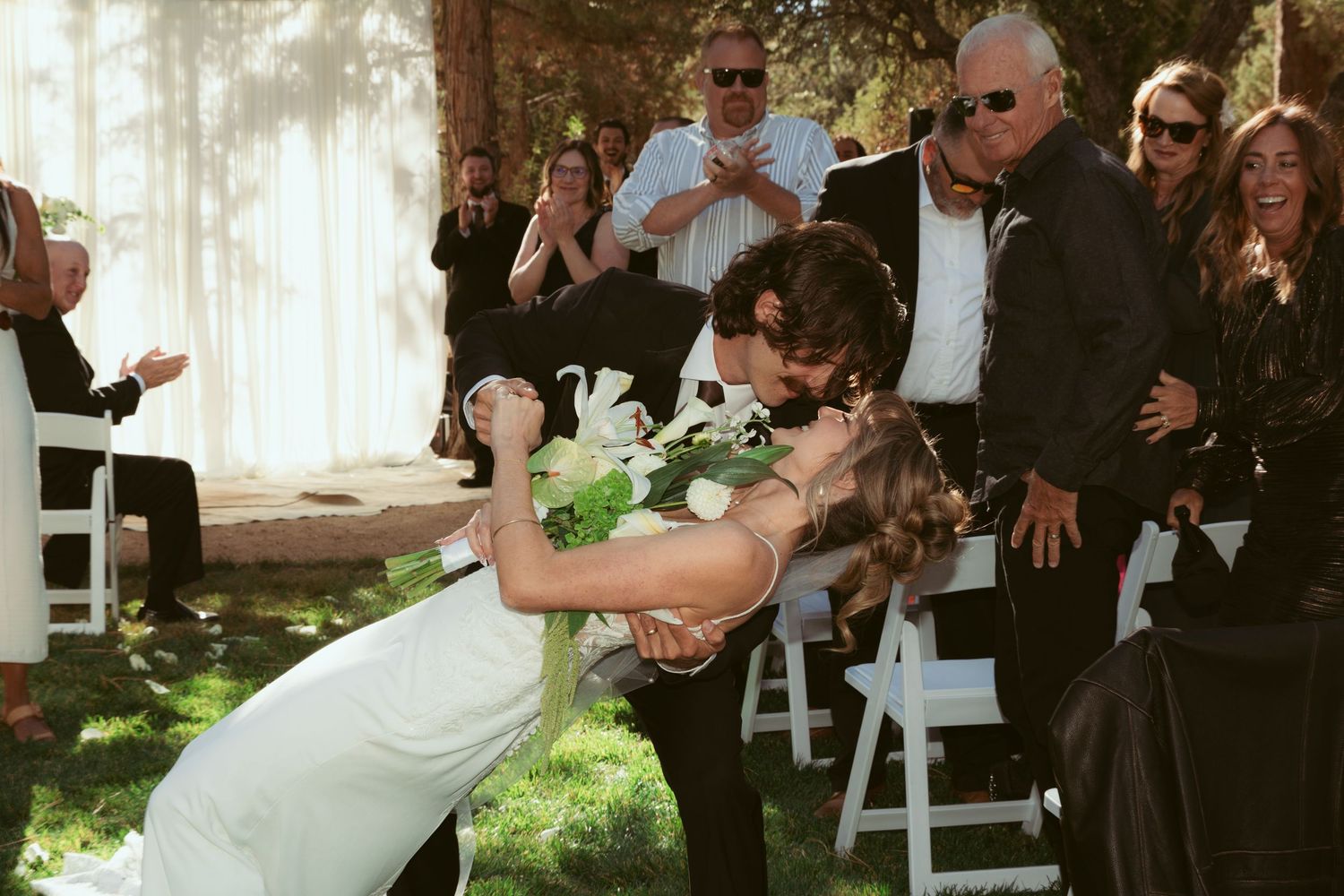 Wedding couple shares their first dance surrounded by guests at an outdoor reception.