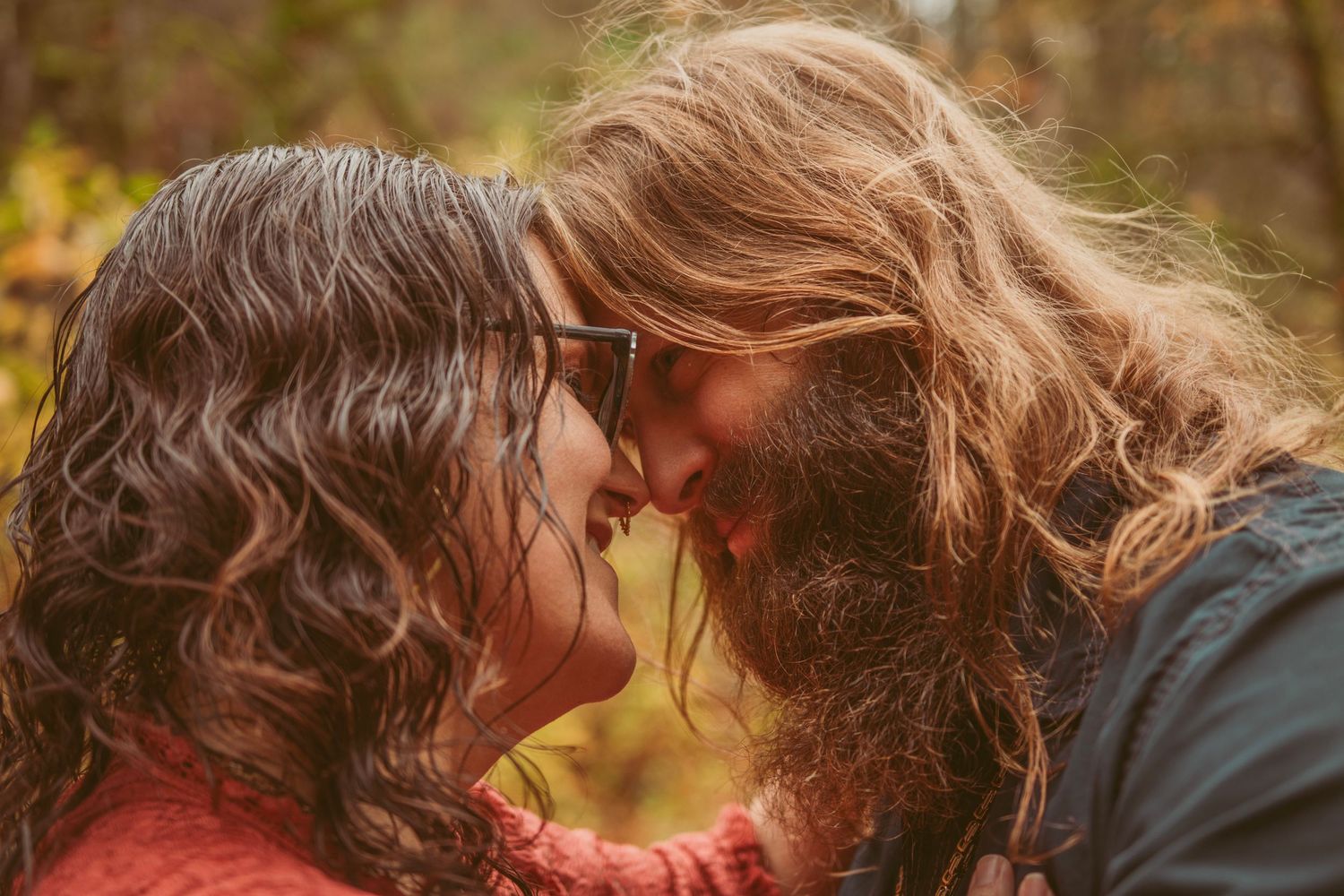 Close up of couple sharing intimate moment in autumn forest setting.