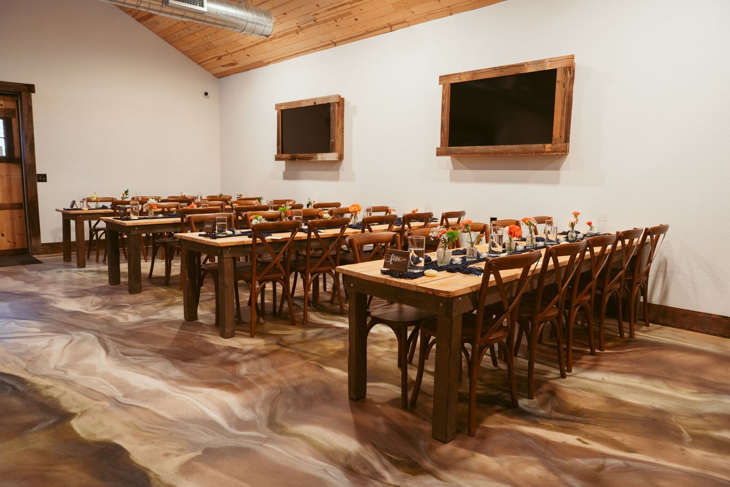 Large reception hall with wooden tables and chairs arranged in rows for an event.