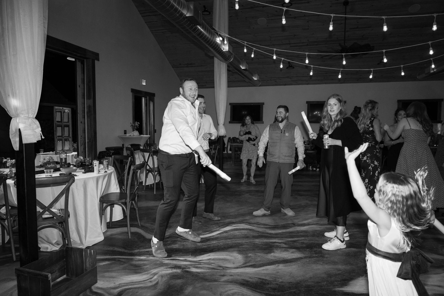 Black and white photo of wedding guests dancing and celebrating on the reception dance floor.