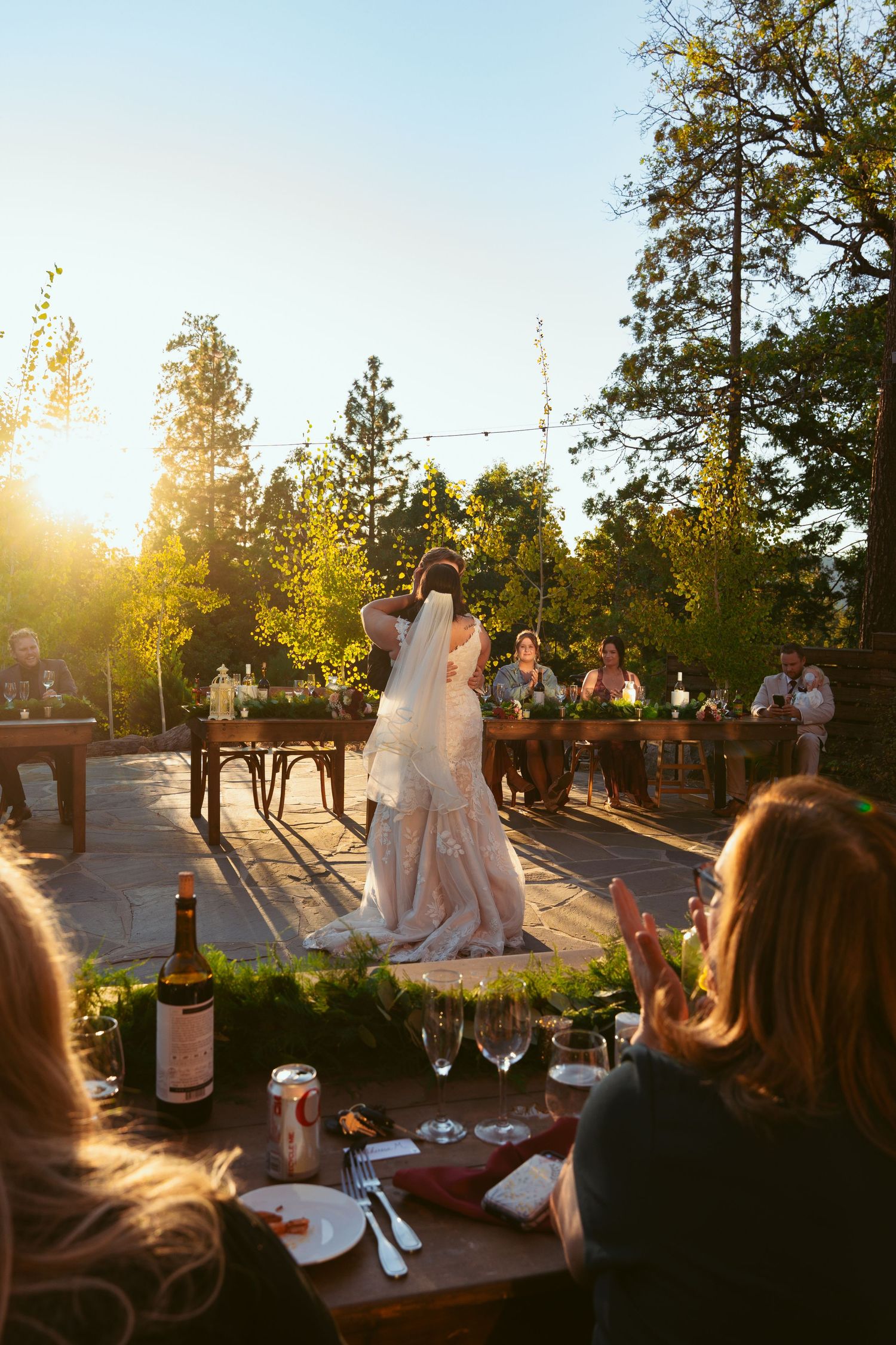 Wedding guests watch a couple's first dance during golden hour at an outdoor reception.