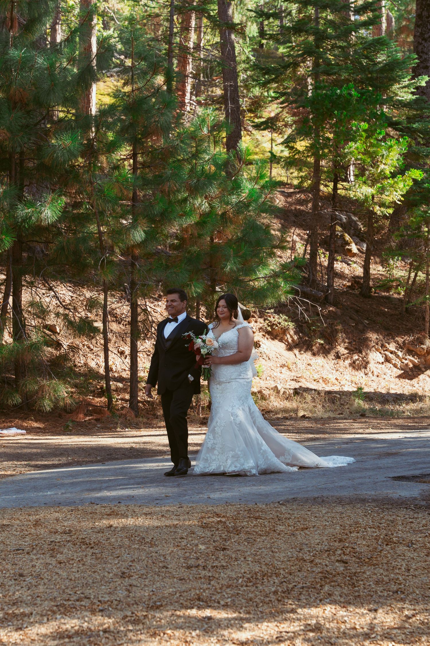 Newlyweds walk together on a forest path after their outdoor wedding ceremony.