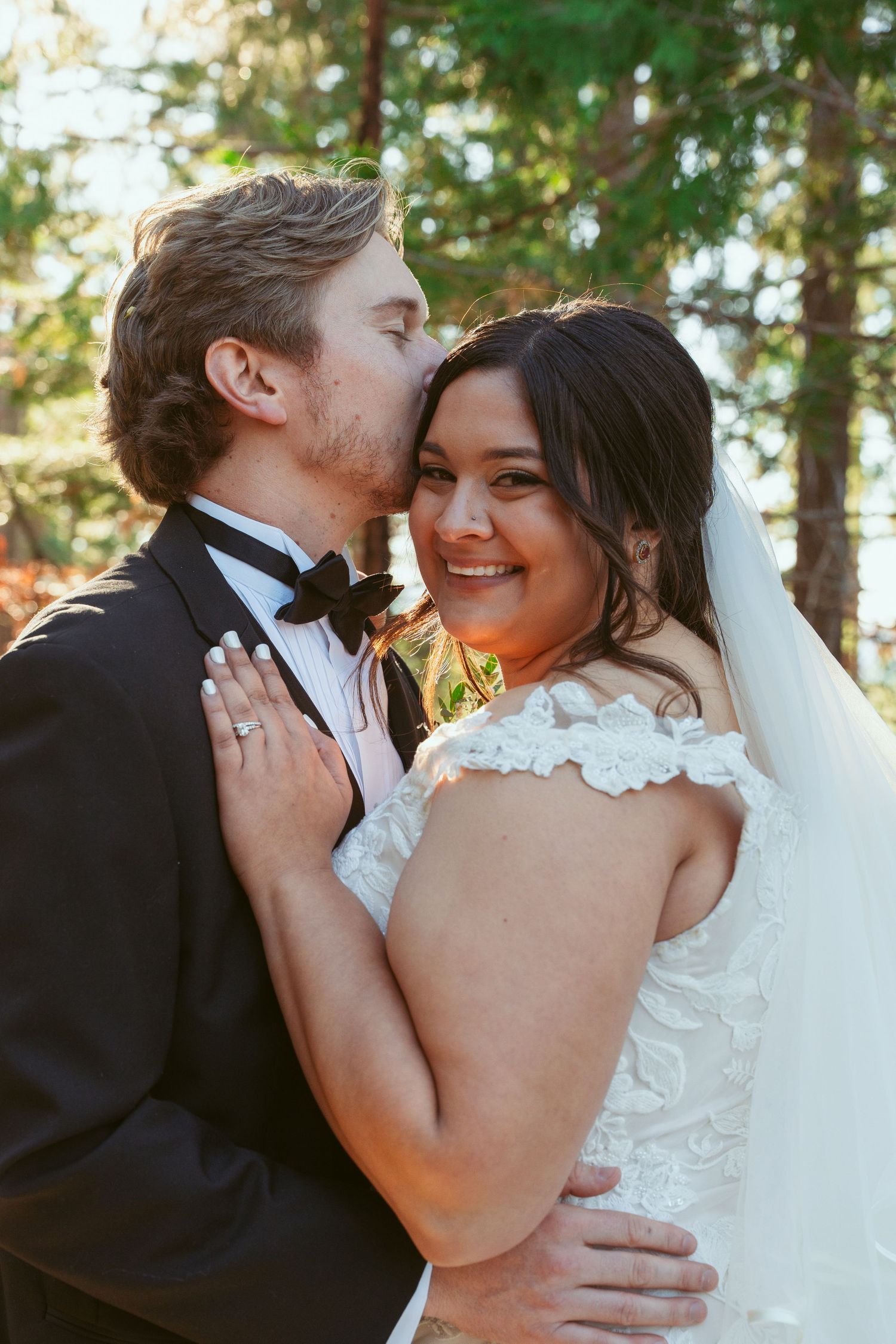 A tender wedding moment captured in golden forest light.