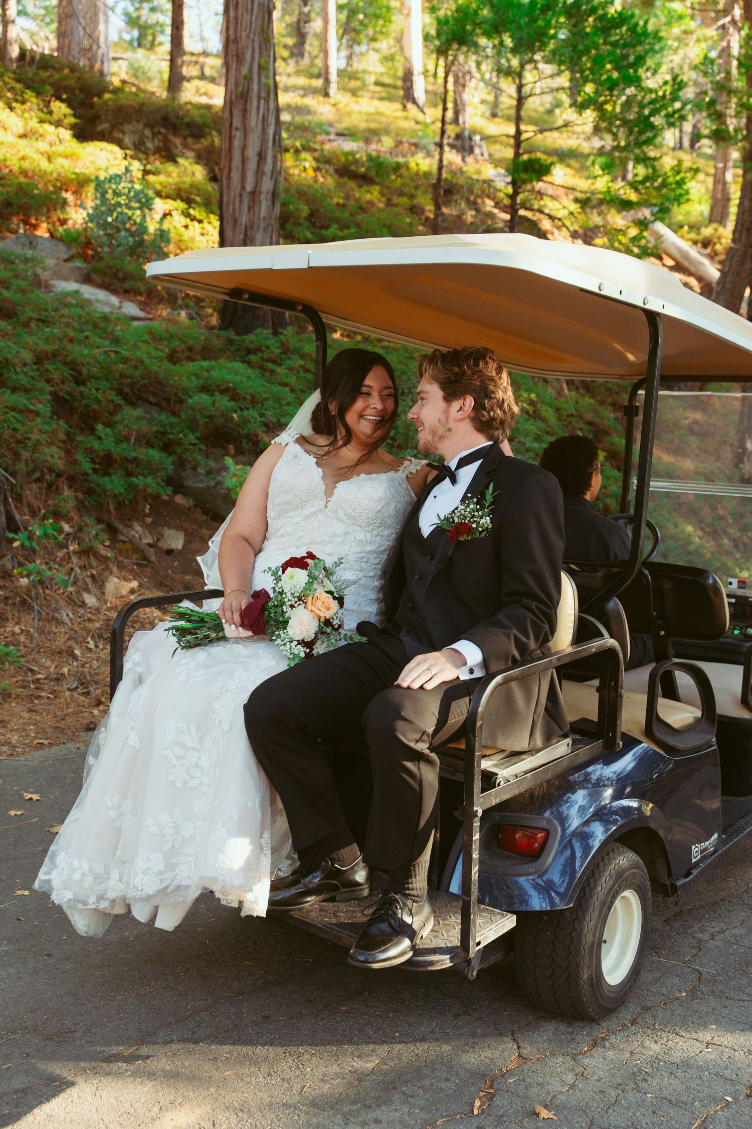 Wedding couple sharing sweet moments in a golf cart on a forest path.