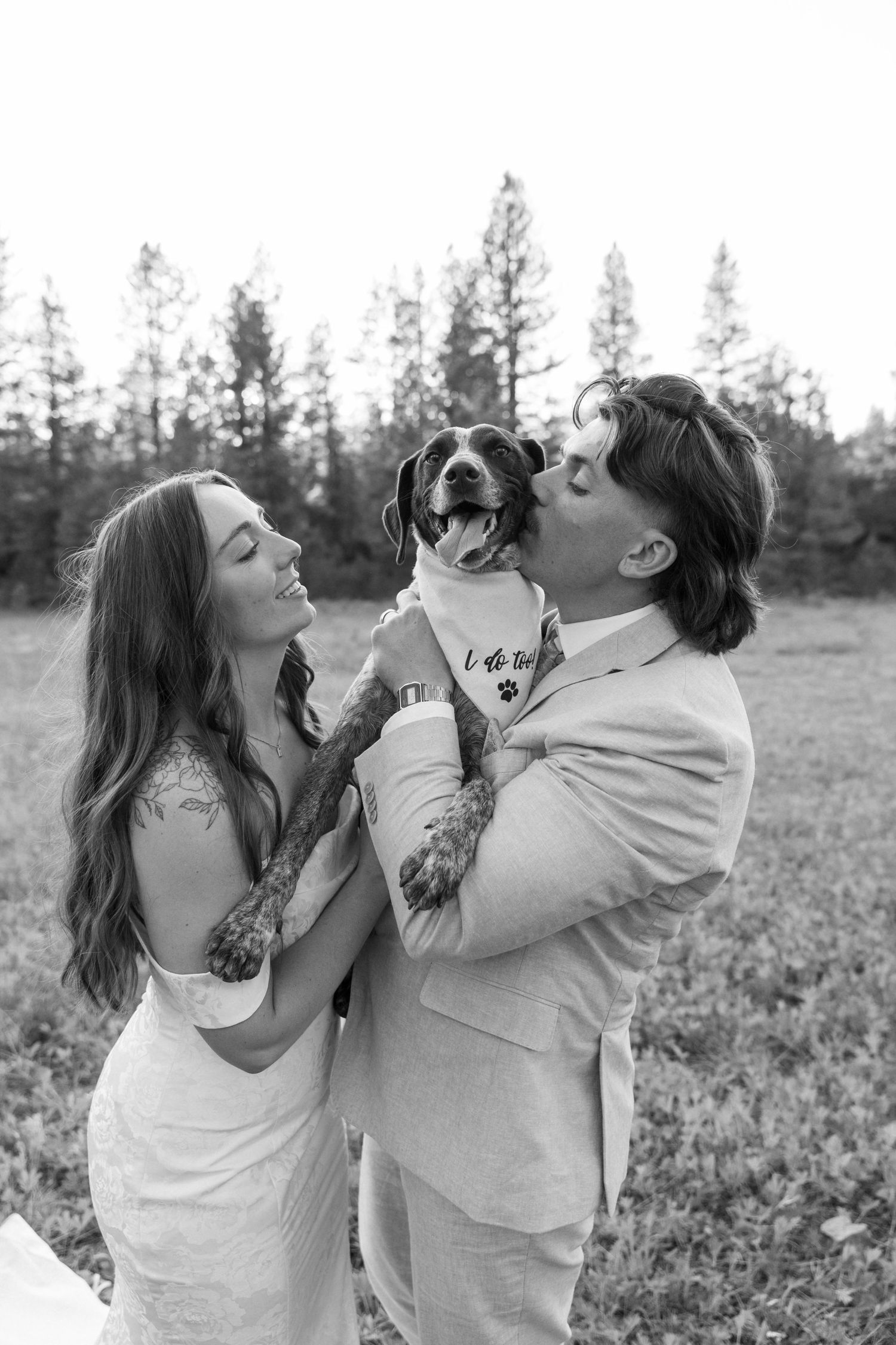 Black and white photos capture playful moments between a couple and their dog in a field.