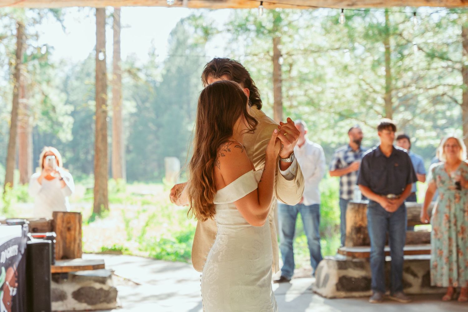 Romantic dance moment captured in a rustic outdoor wedding venue with natural lighting.