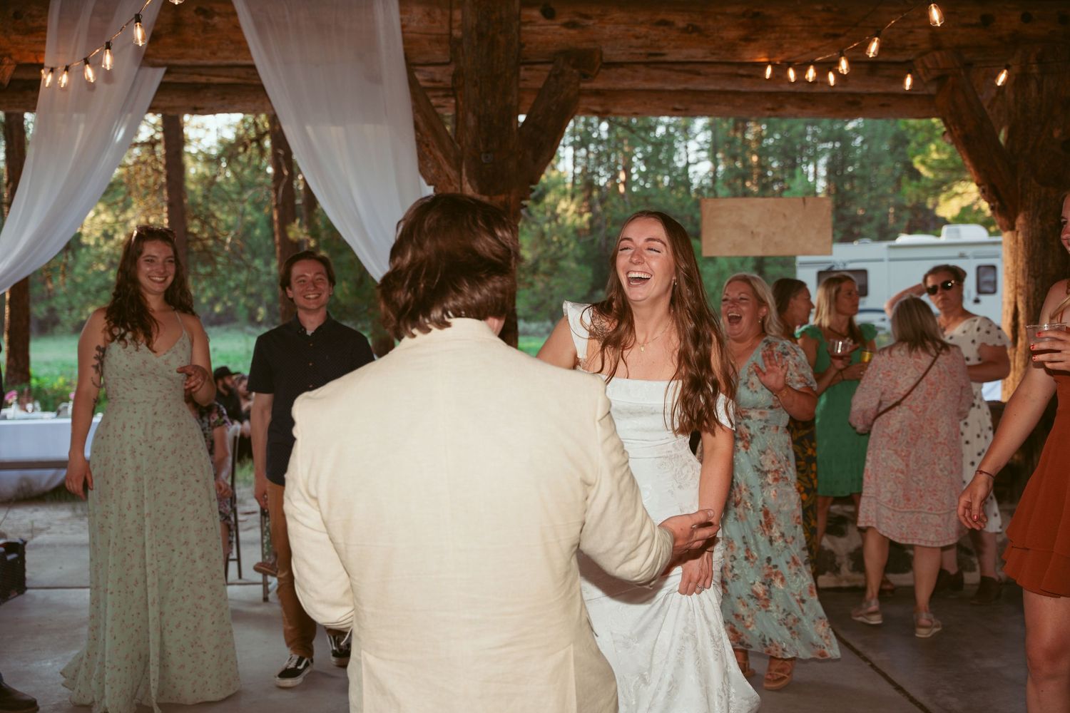 Wedding reception in a rustic wooden barn venue with string lights and white drapes.