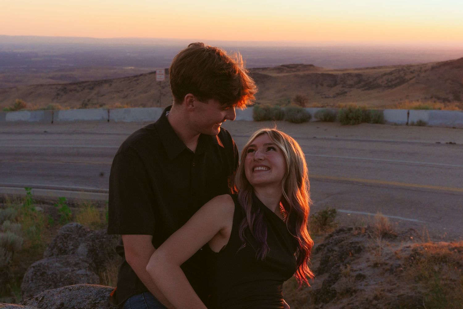 Sunset portrait of couple laughing together with golden light and mountain vista.