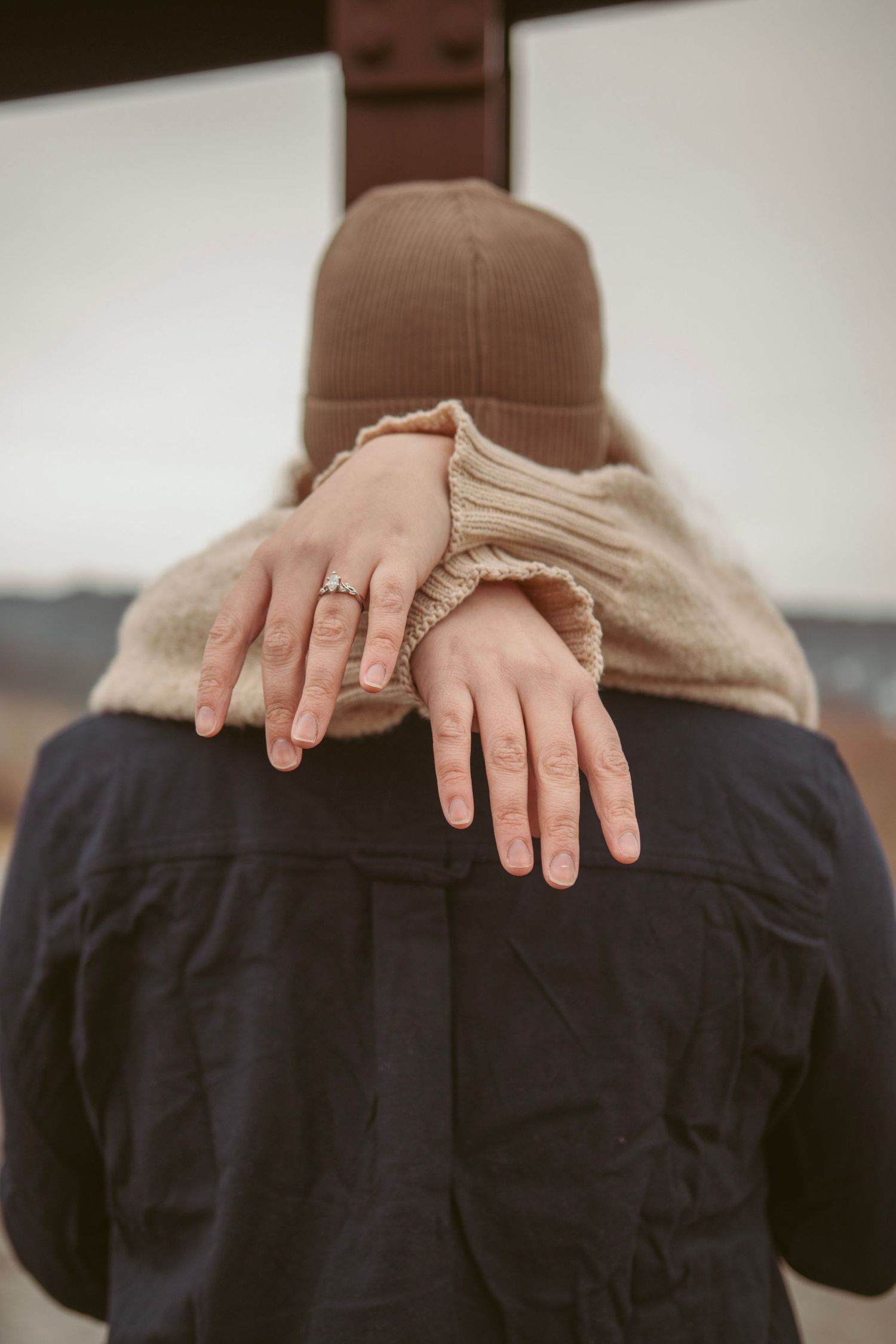 Close-up shot of hands resting gently on dark fabric.