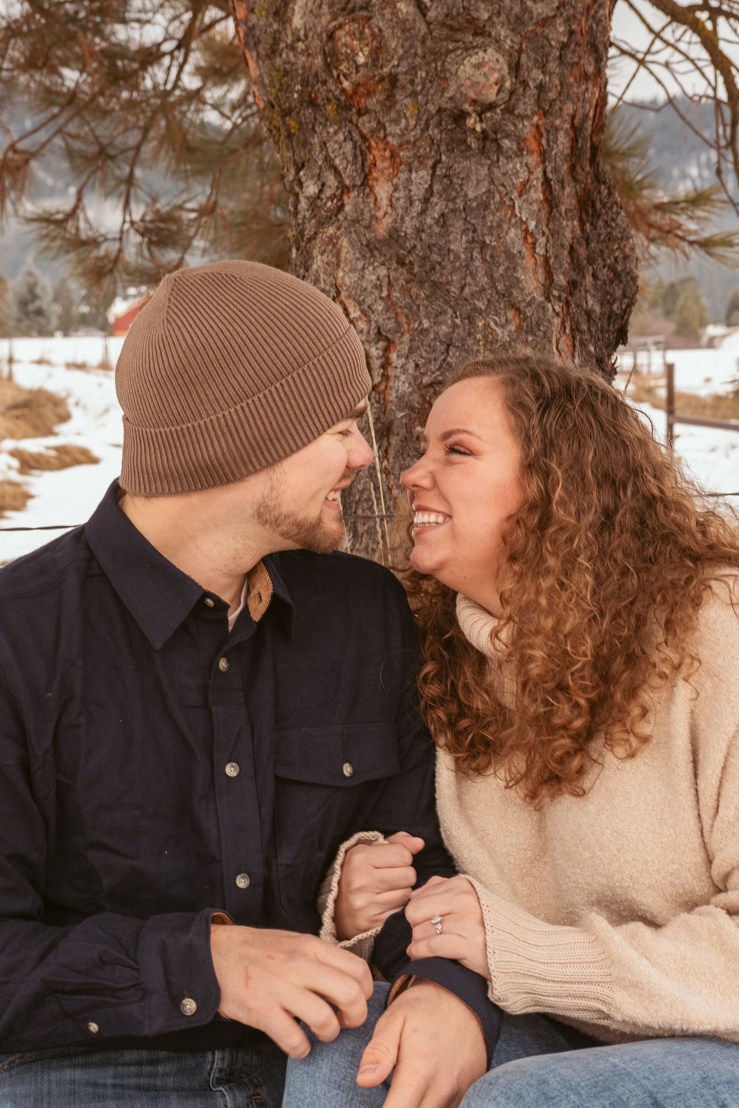 Couple sharing intimate moments on snowy mountain landscape wearing cozy winter attire.