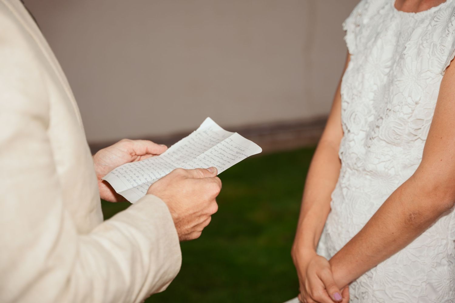 Two people share intimate written messages during an outdoor wedding ceremony.