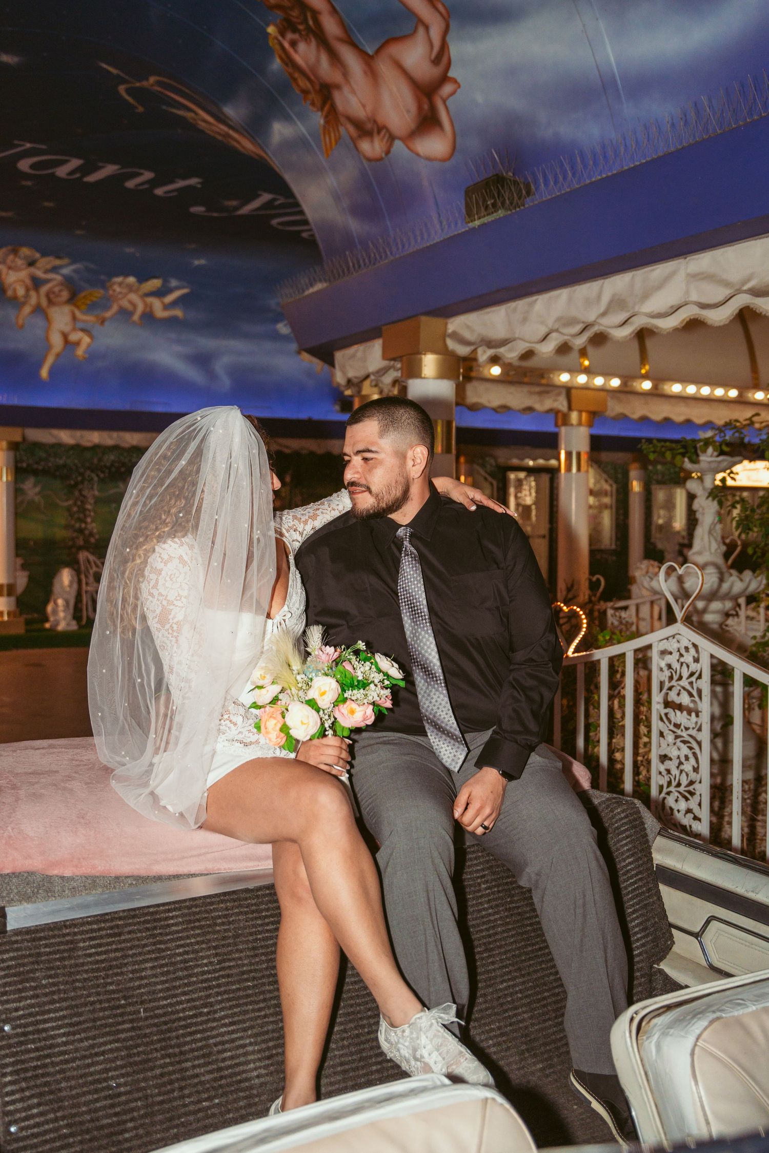 A romantic scene under twinkling lights at an outdoor wedding venue.
