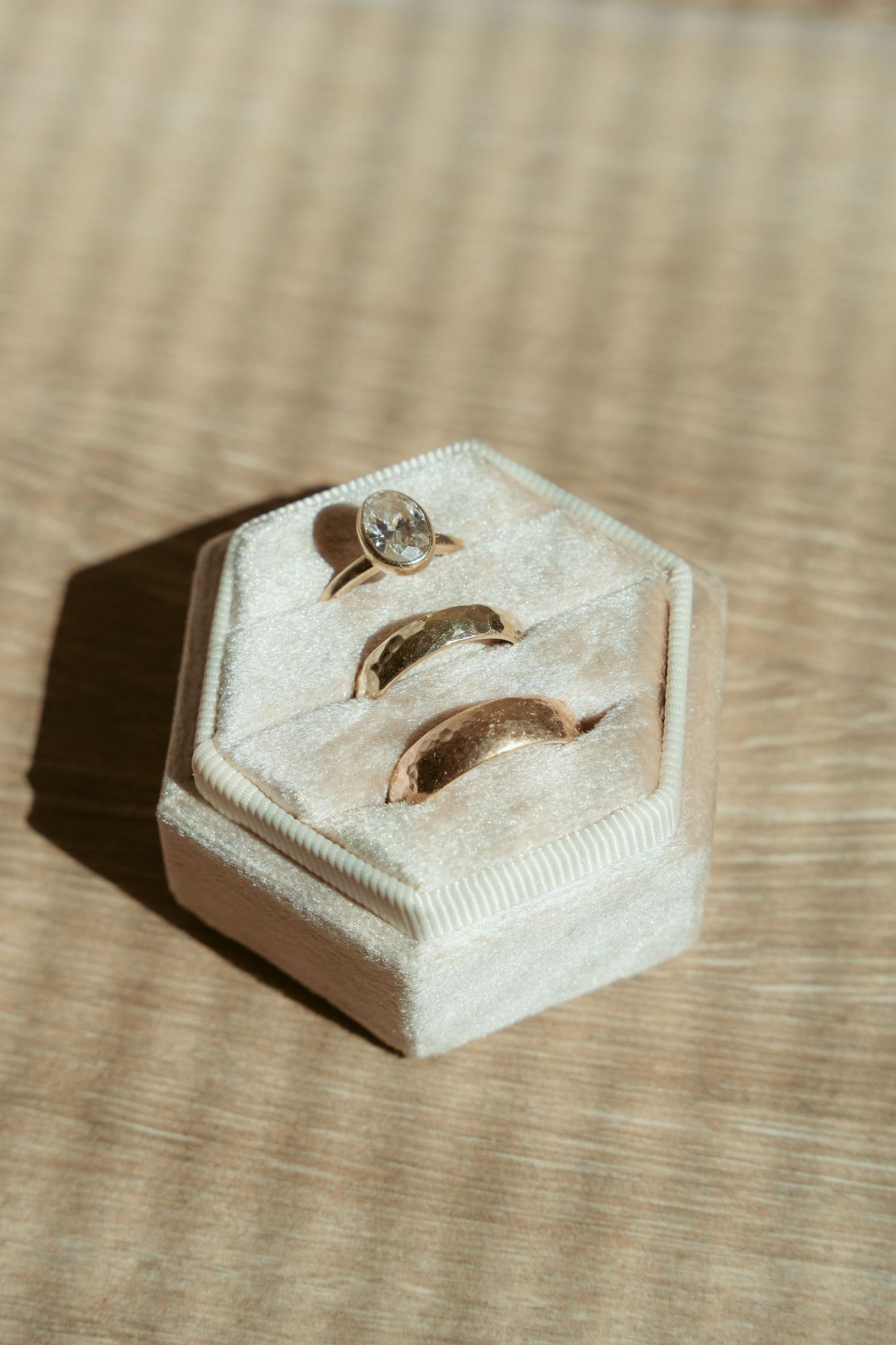 Wedding rings displayed on white hexagonal ring holders against a textured surface.