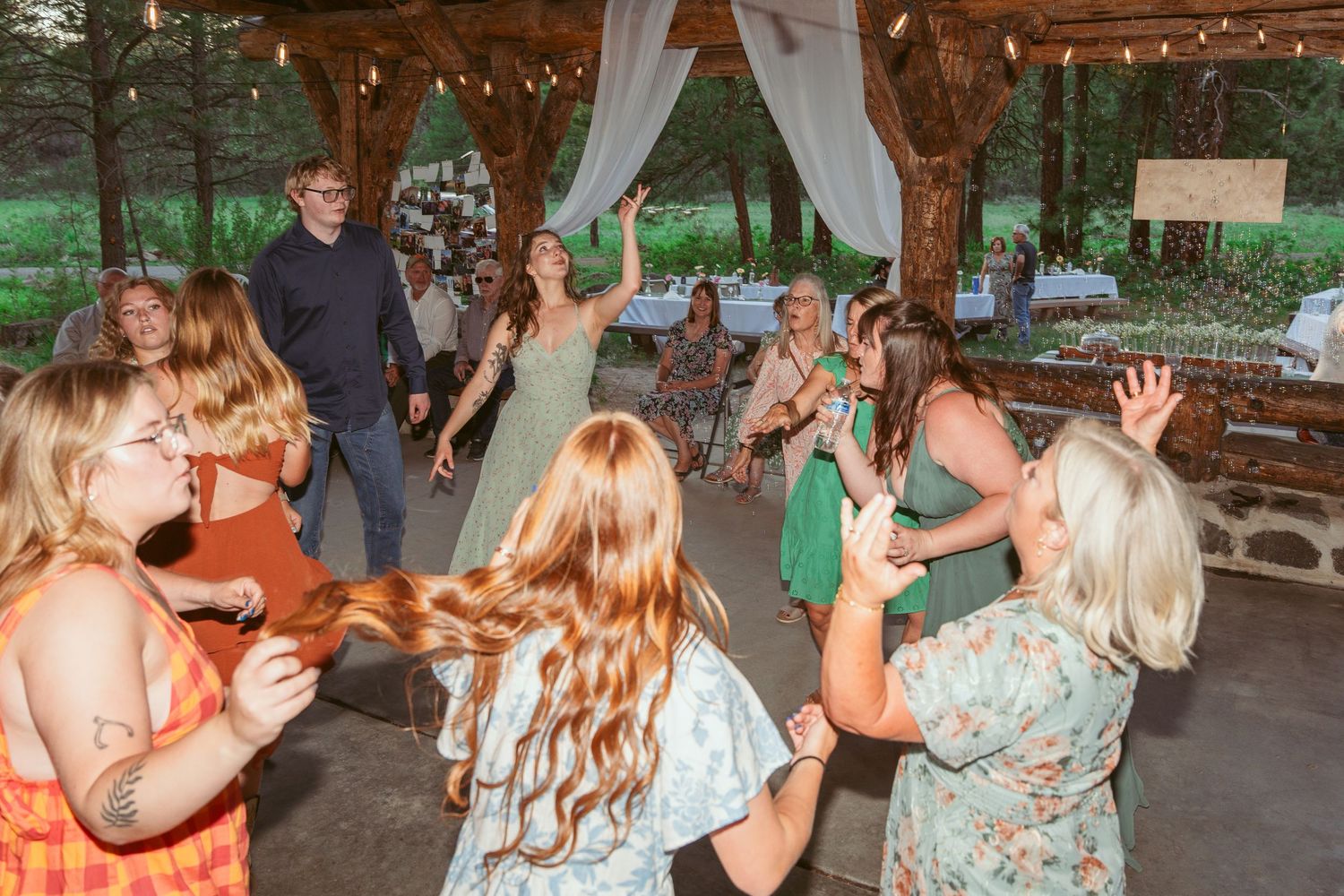 People dancing and socializing at a rustic outdoor wedding reception venue.