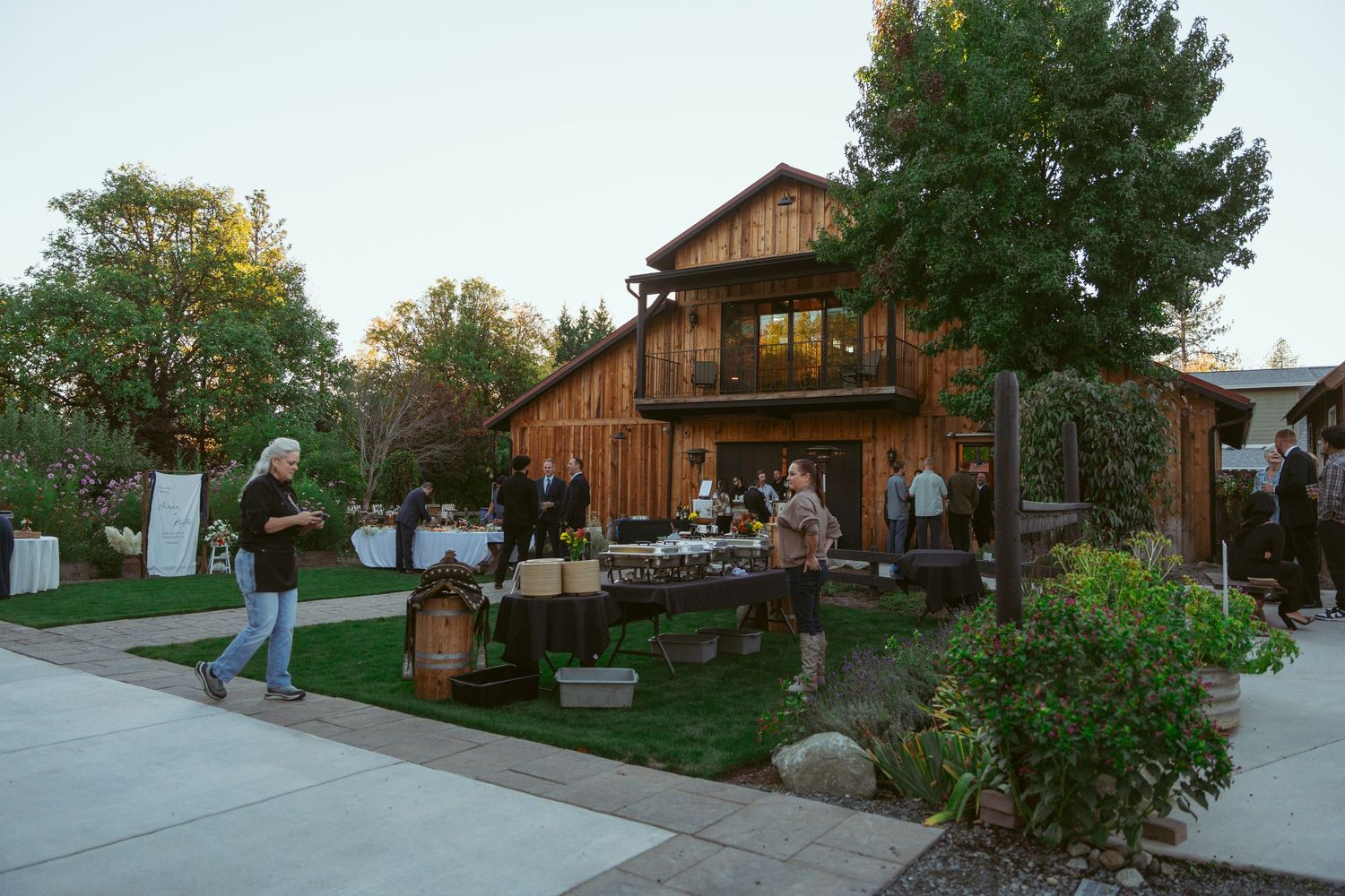 Rustic barn wedding venue with outdoor seating and garden decor at sunset.