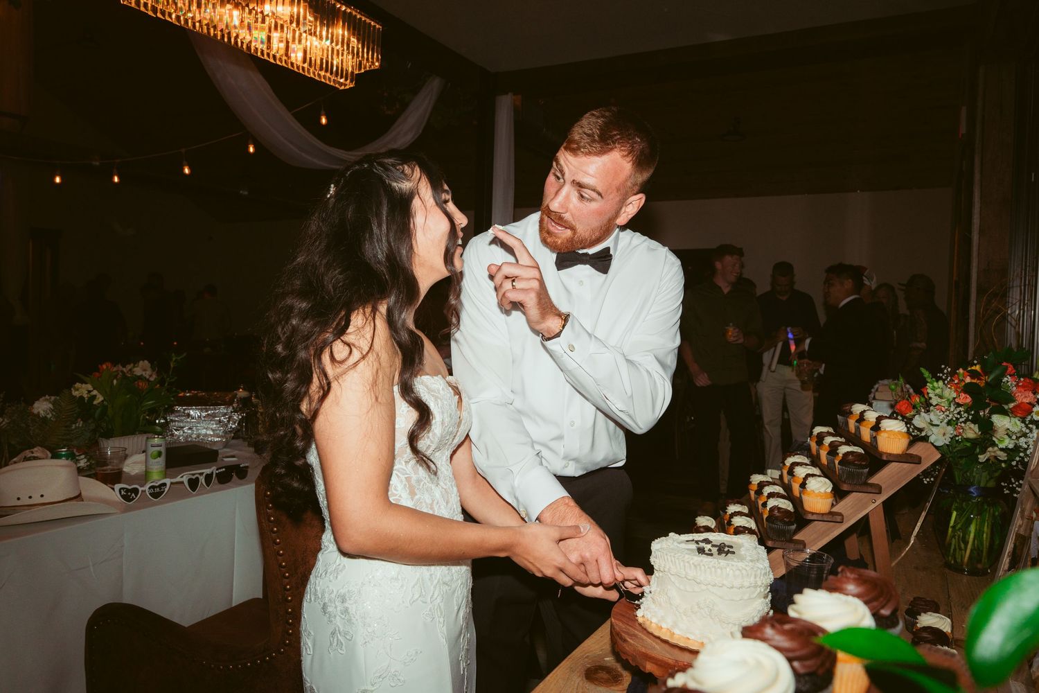 Wedding couple enjoys a fun cake-cutting moment during their evening reception celebration.