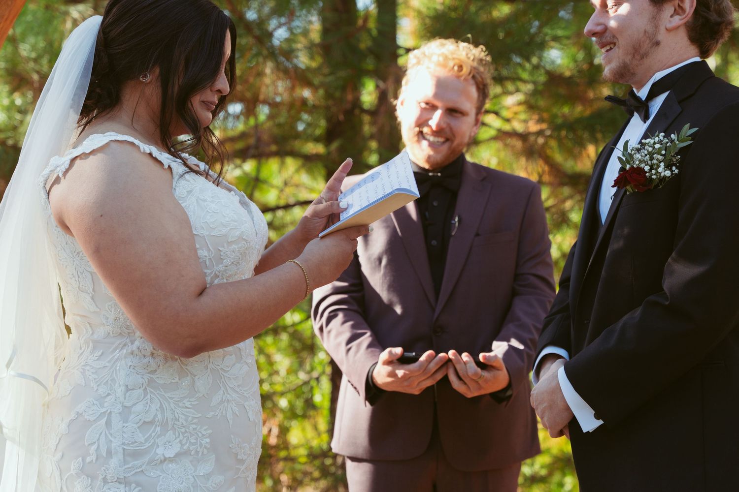 Joyful wedding ceremony moments under wooden pergola in forest setting.