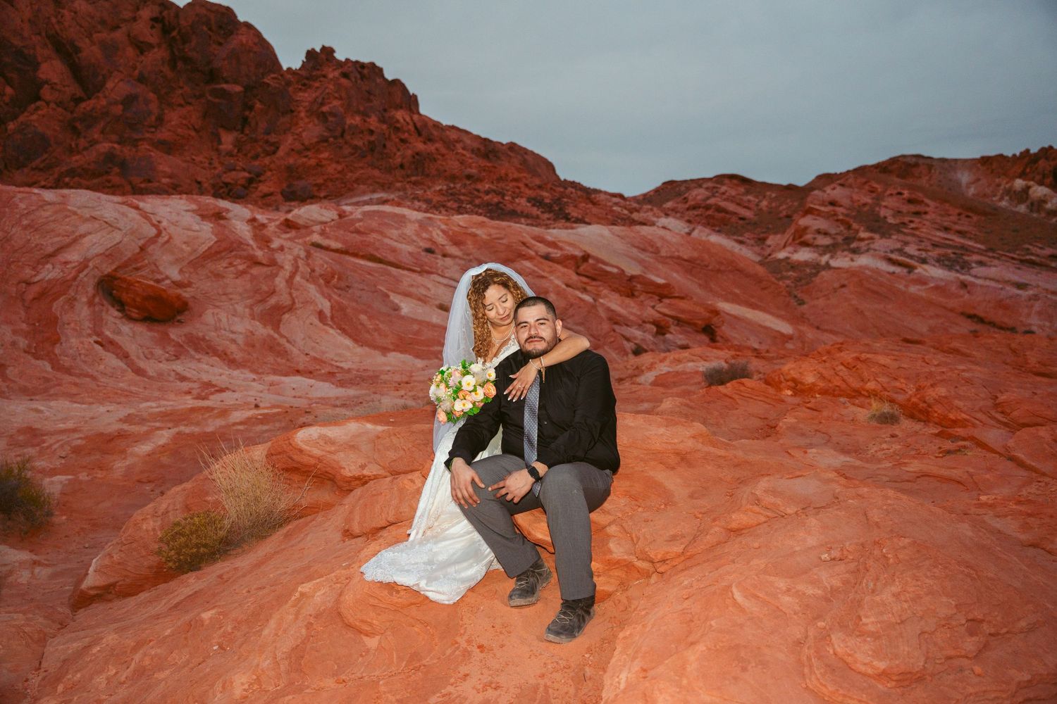Wedding photography session on vibrant red rock formations under blue sky.