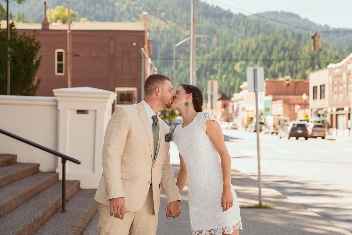 Newlyweds strolling together on a sidewalk with mountains in the background.