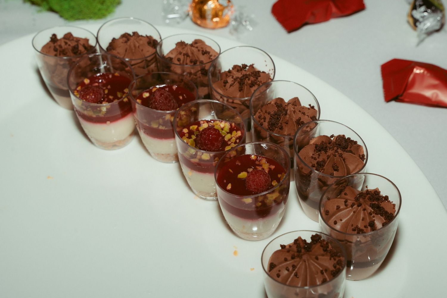 Individual chocolate mousse desserts served in small glass cups on a white plate.