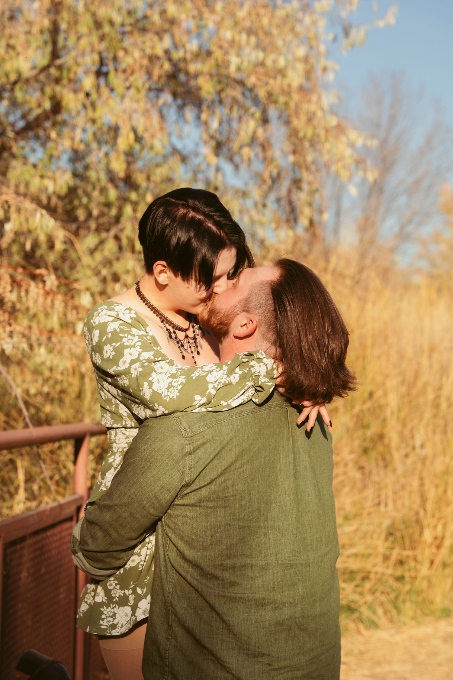 A romantic couple shares tender moments during a sunset photoshoot in nature.