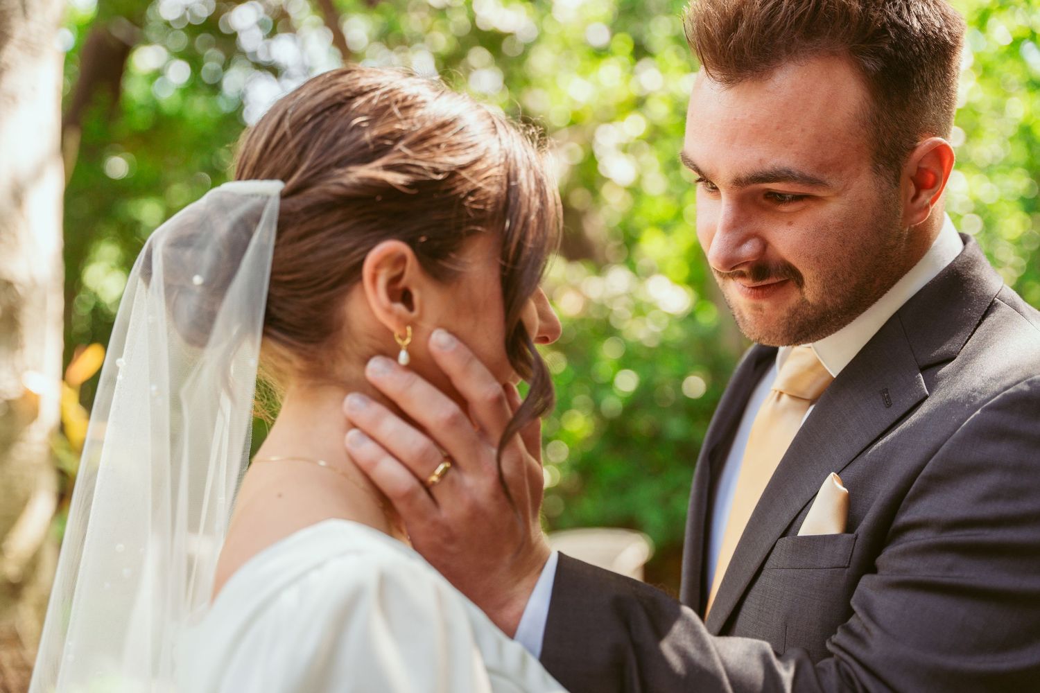 Romantic wedding moment captured outdoors with soft natural lighting and greenery.