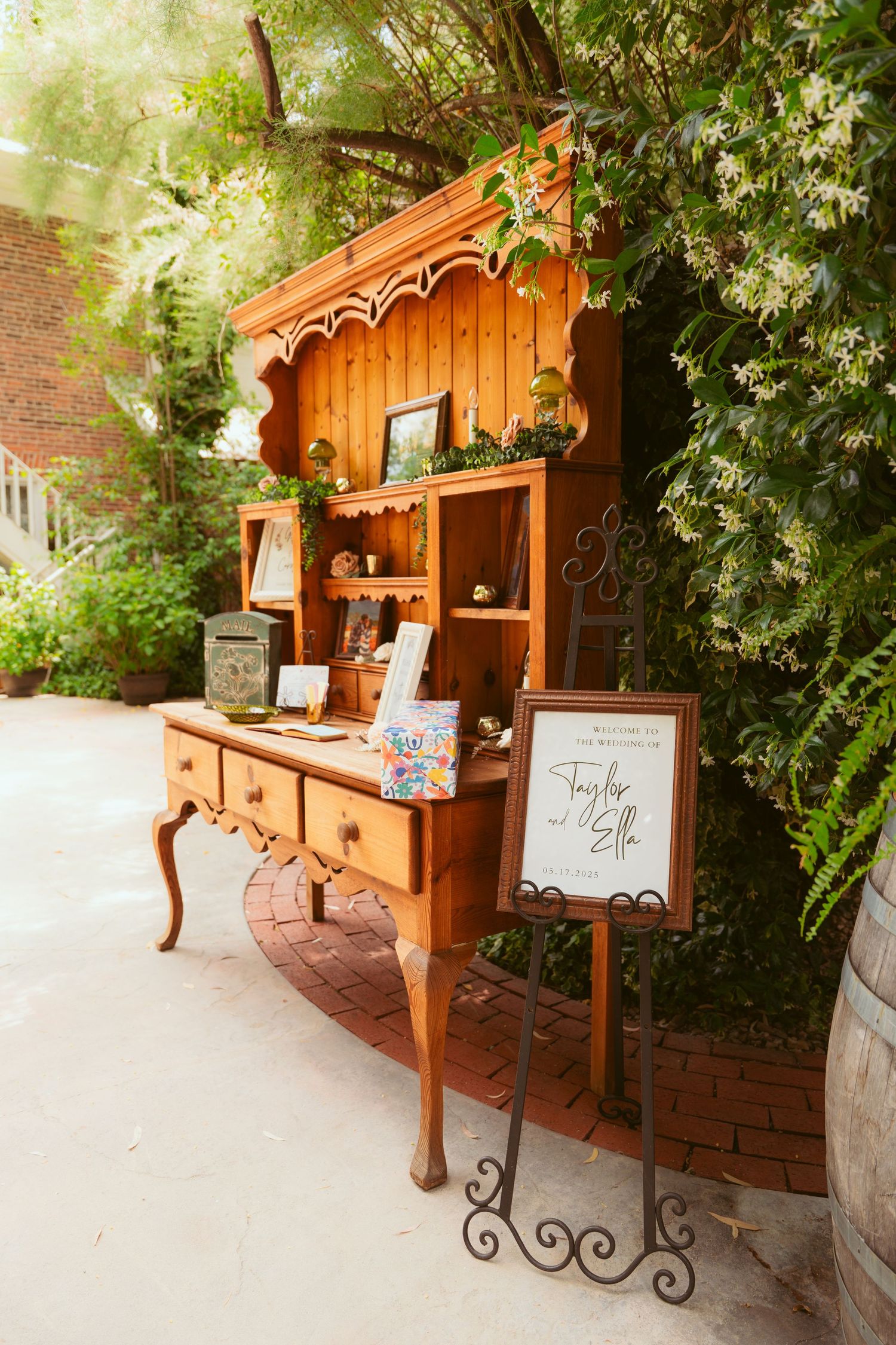A rustic wooden welcome station with decorative signs and floral arrangements at an outdoor venue.
