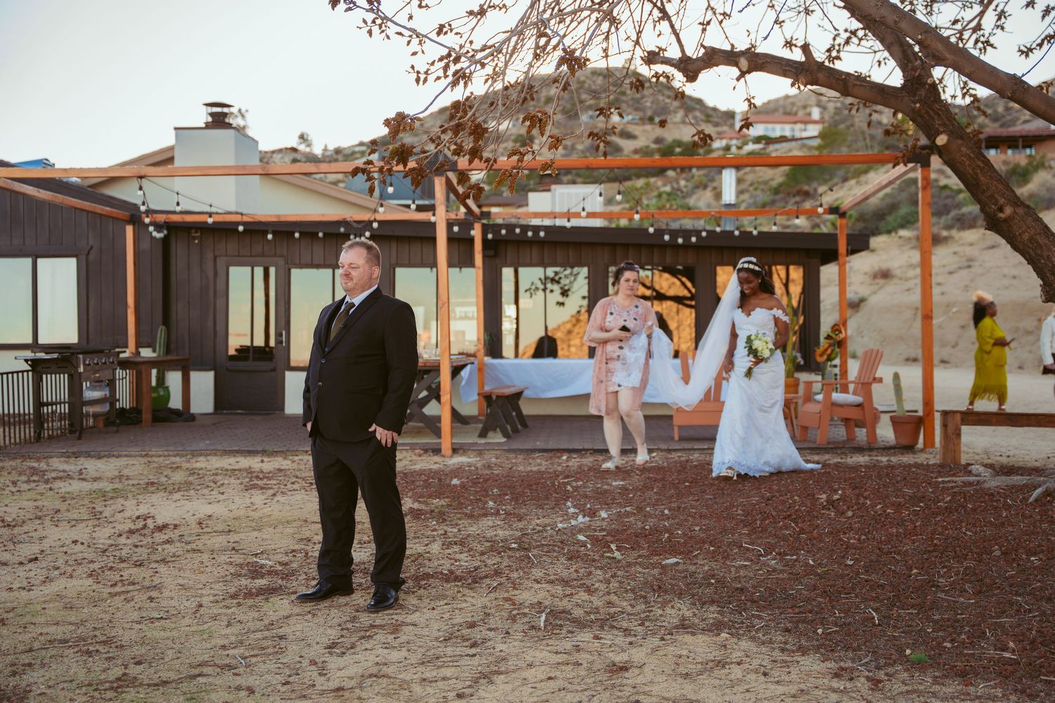 Outdoor wedding venue with string lights and desert mountain backdrop at dusk.