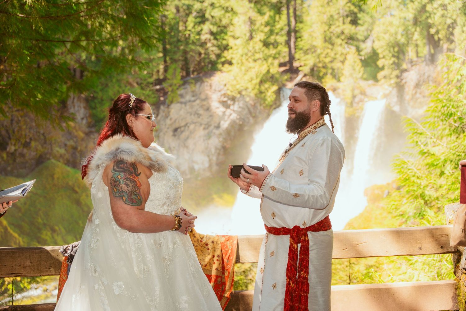 Forest wedding ceremony with natural greenery and waterfall backdrop.