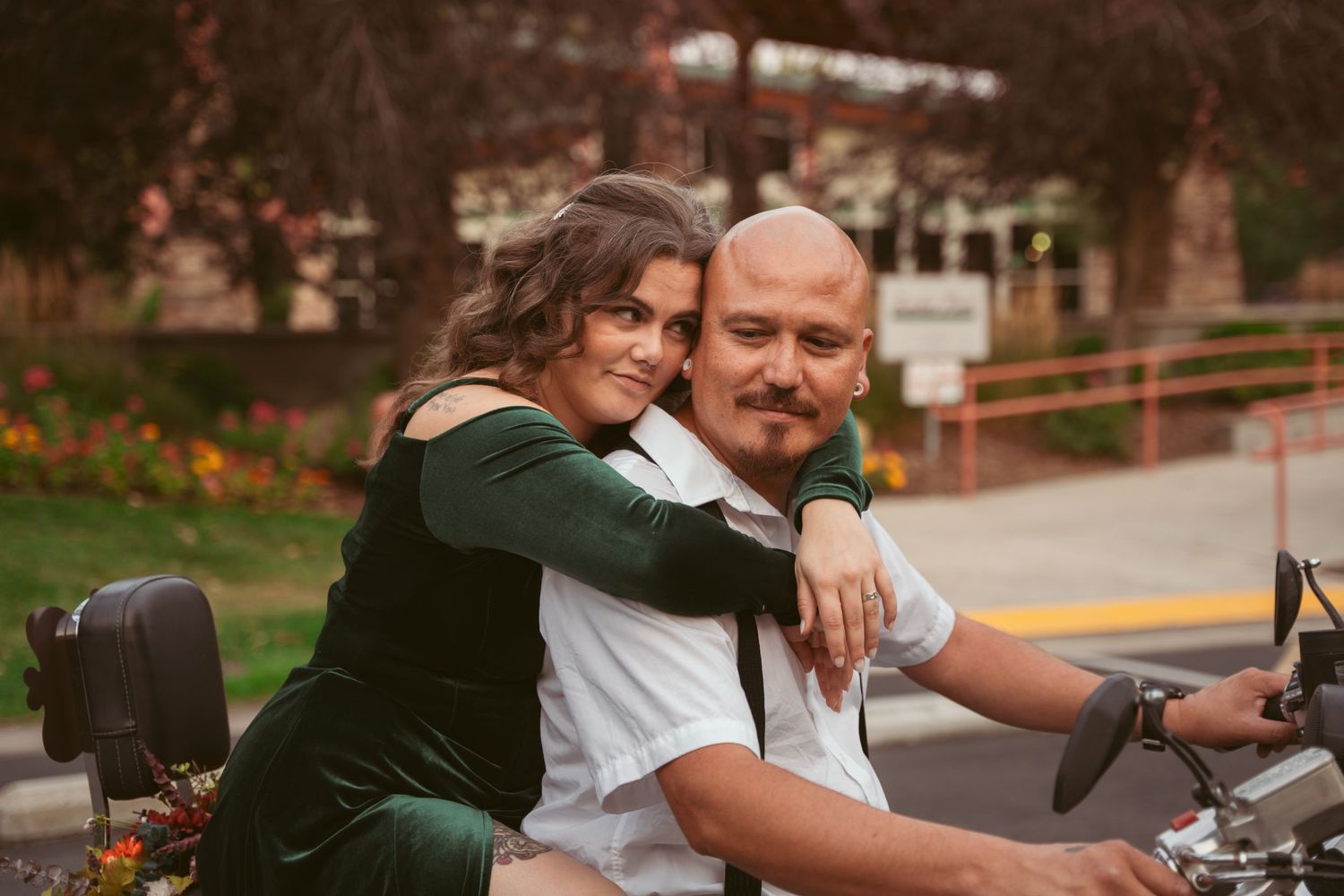 A couple shares a joyful embrace near a motorcycle.