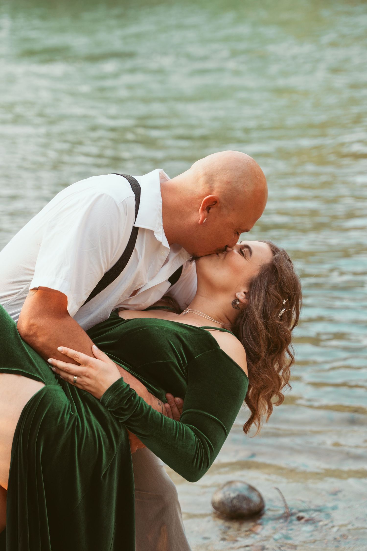 A romantic dip pose near the water's edge with dramatic lighting.