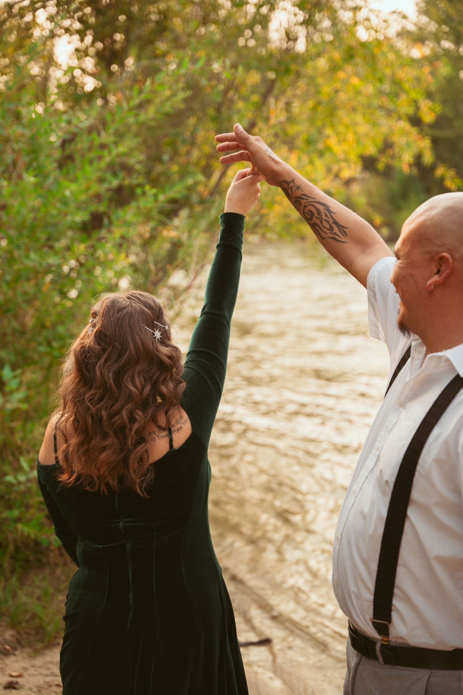 A couple dancing together outdoors in autumn, with the person in green velvet dress being twirled by their partner.