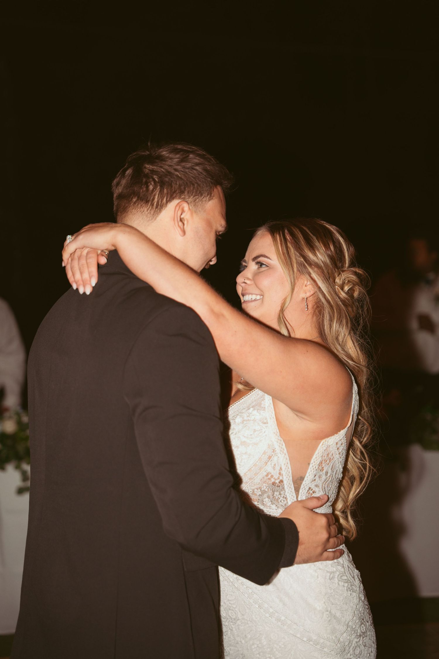 A romantic first dance moment between newlyweds at a wedding reception under dim lighting.