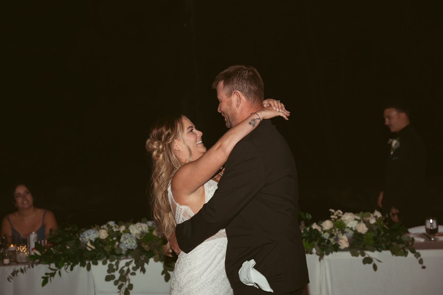 Couples share romantic dances on a dimly lit outdoor dance floor during an evening wedding celebration.