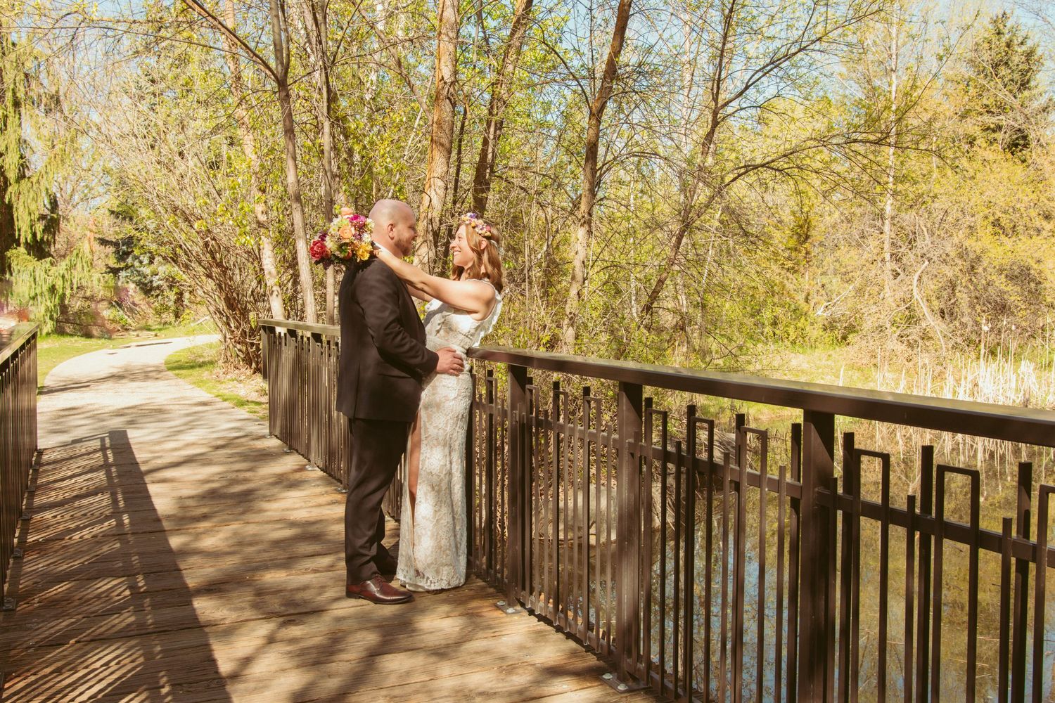 Couple shares romantic moment on wooden bridge surrounded by spring trees.