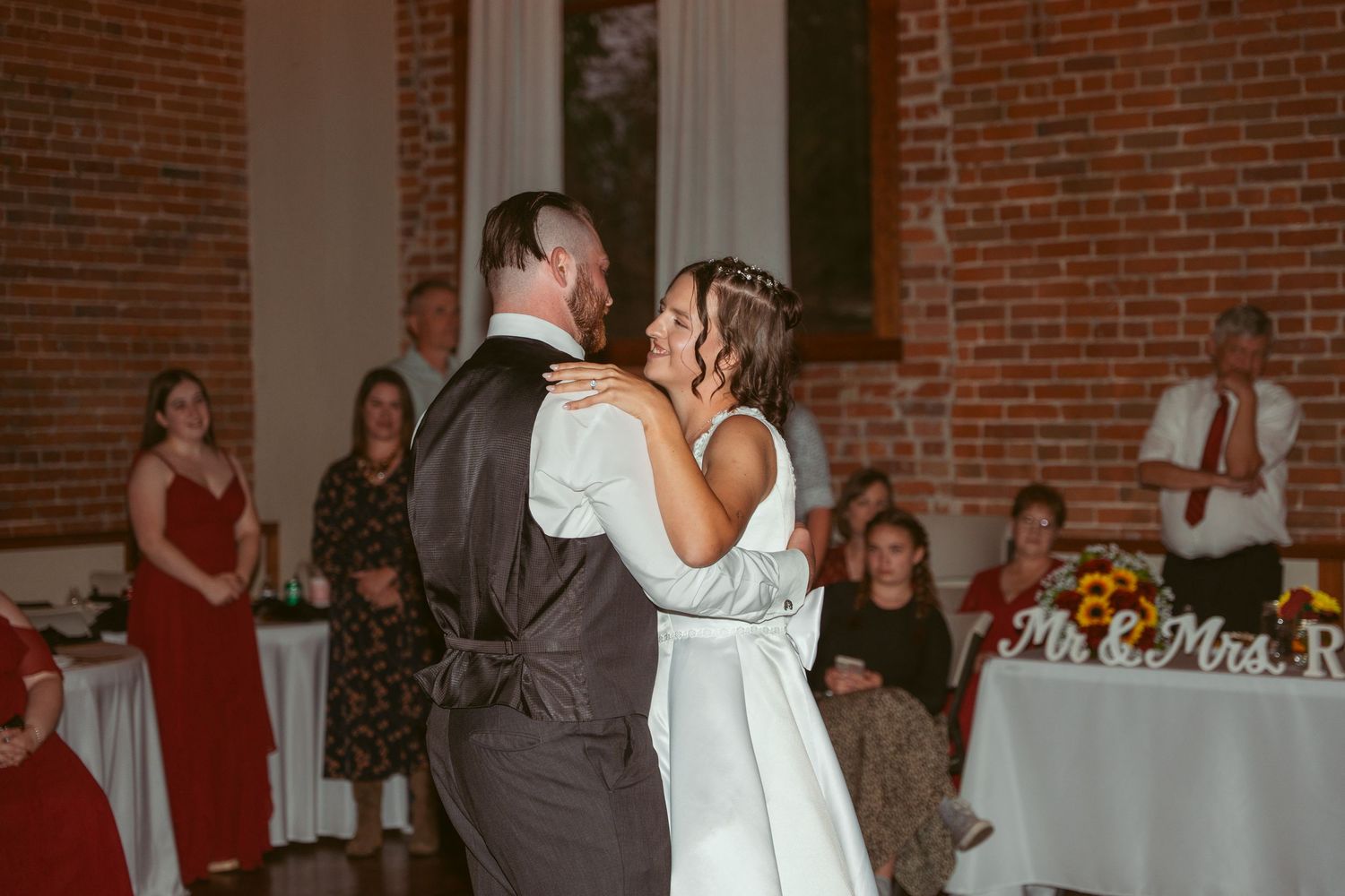 Wedding couple performs romantic dance moves in a spacious industrial-style venue.