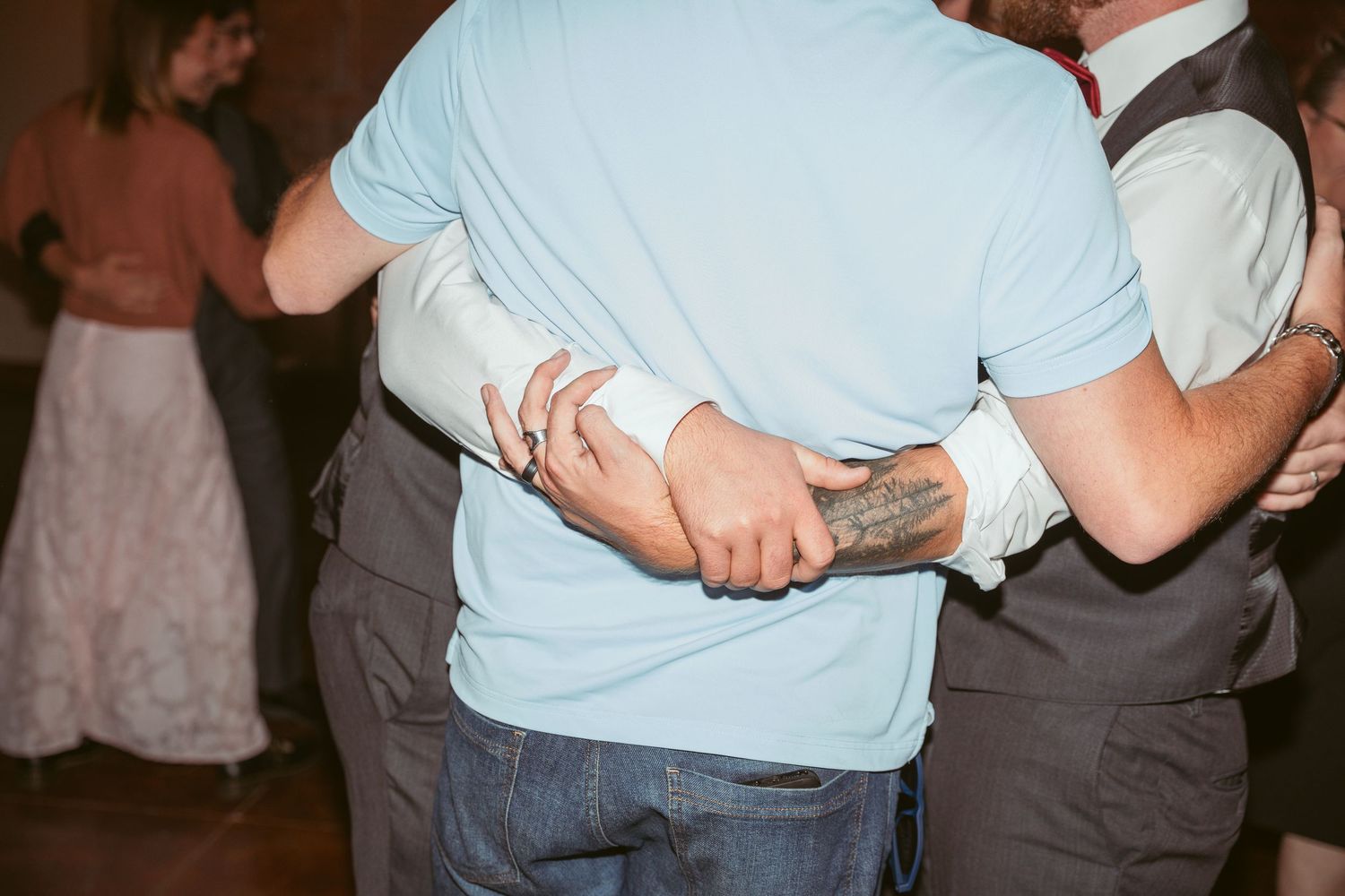 Group of people in formal attire dancing closely at a wedding reception.