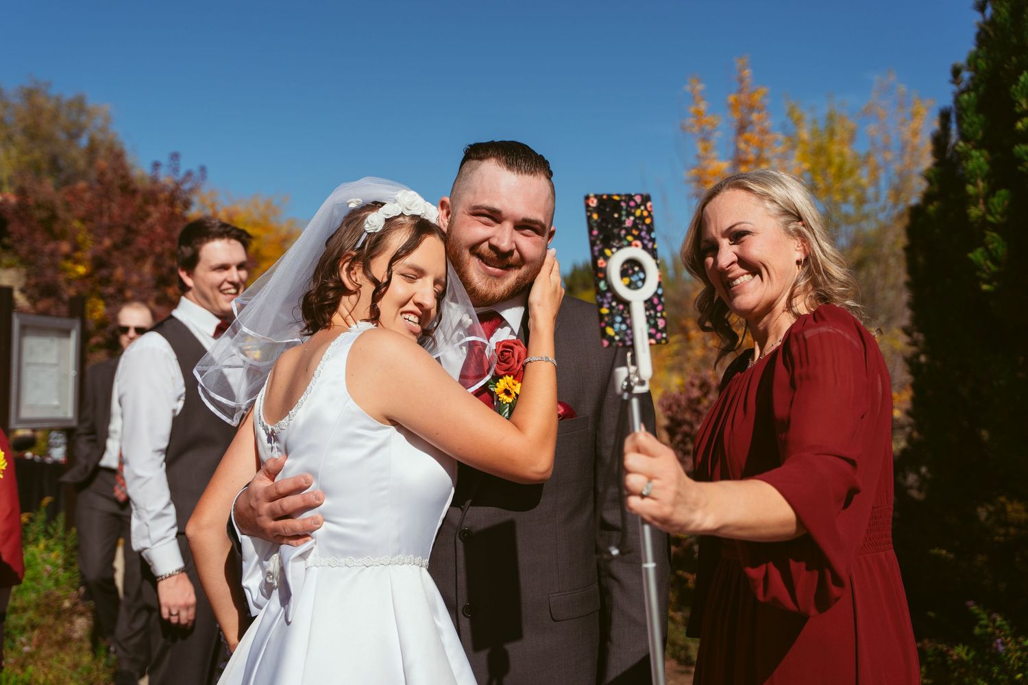 Wedding celebration outdoors with bridal party in burgundy and gray attire.