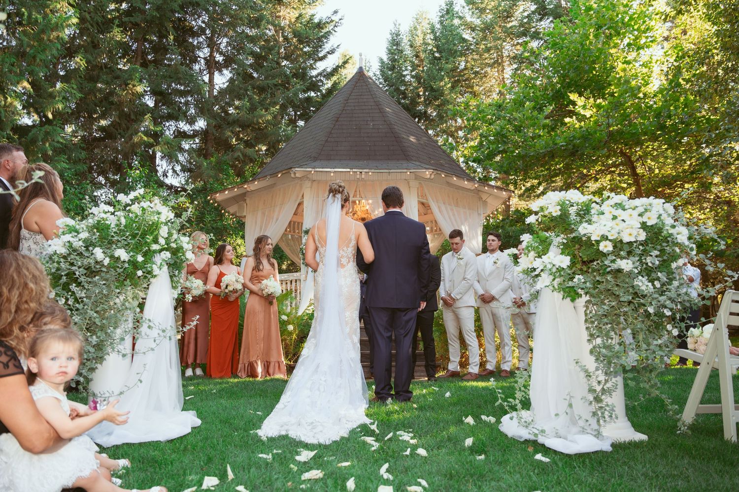 Garden wedding ceremony setup with white gazebo and chairs arranged on manicured lawn.