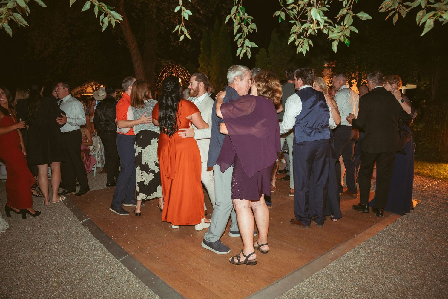 Guests gather on a dark outdoor patio during an evening wedding reception.