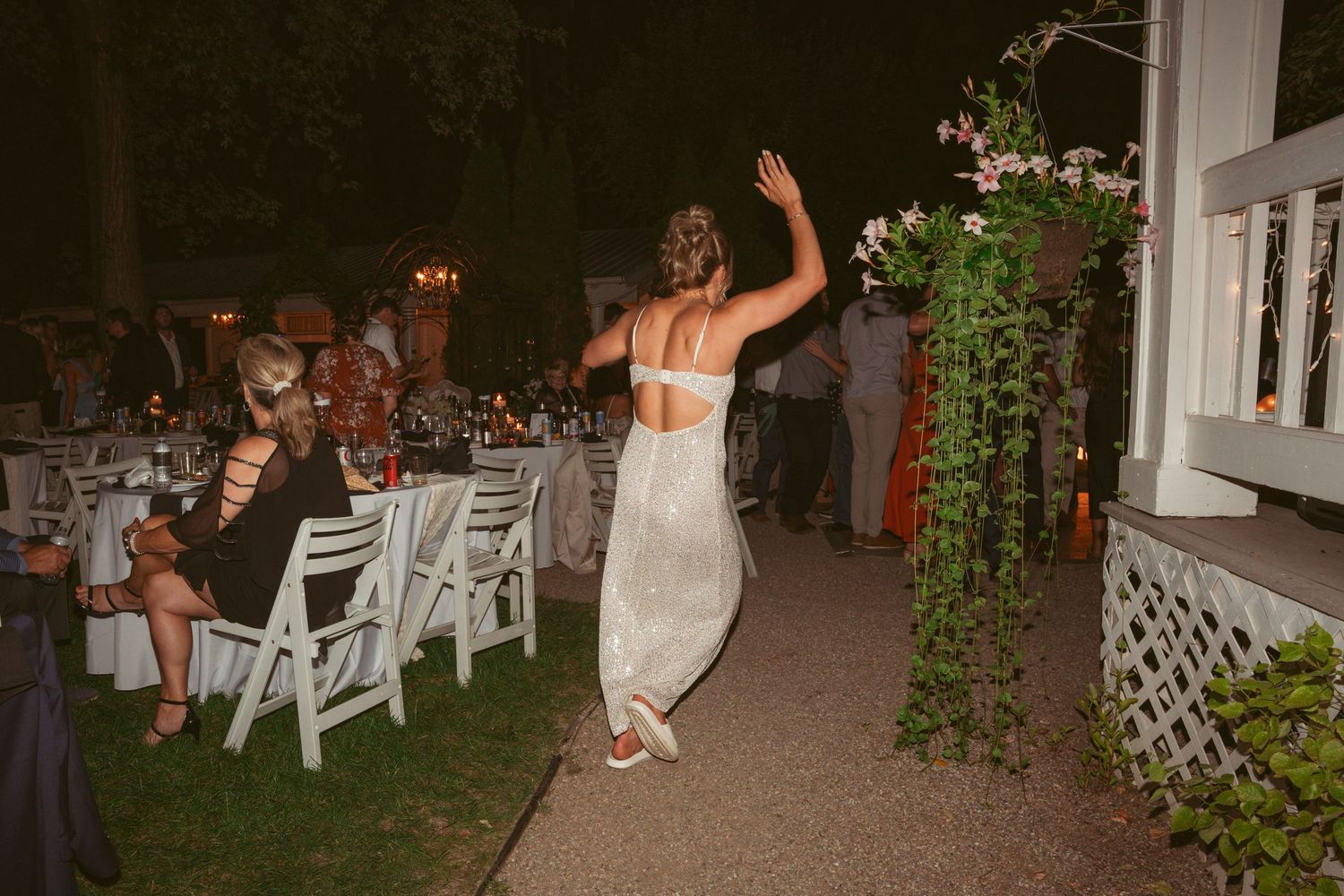 Wedding reception outdoor venue with white chairs and climbing vines in the evening.