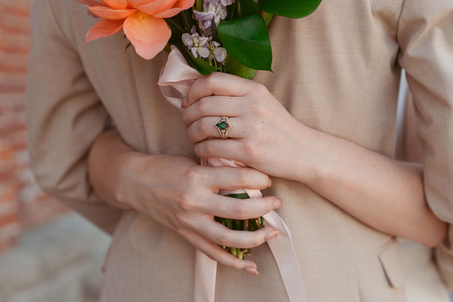 Close-up details of coral and peach wedding bouquet with greenery.