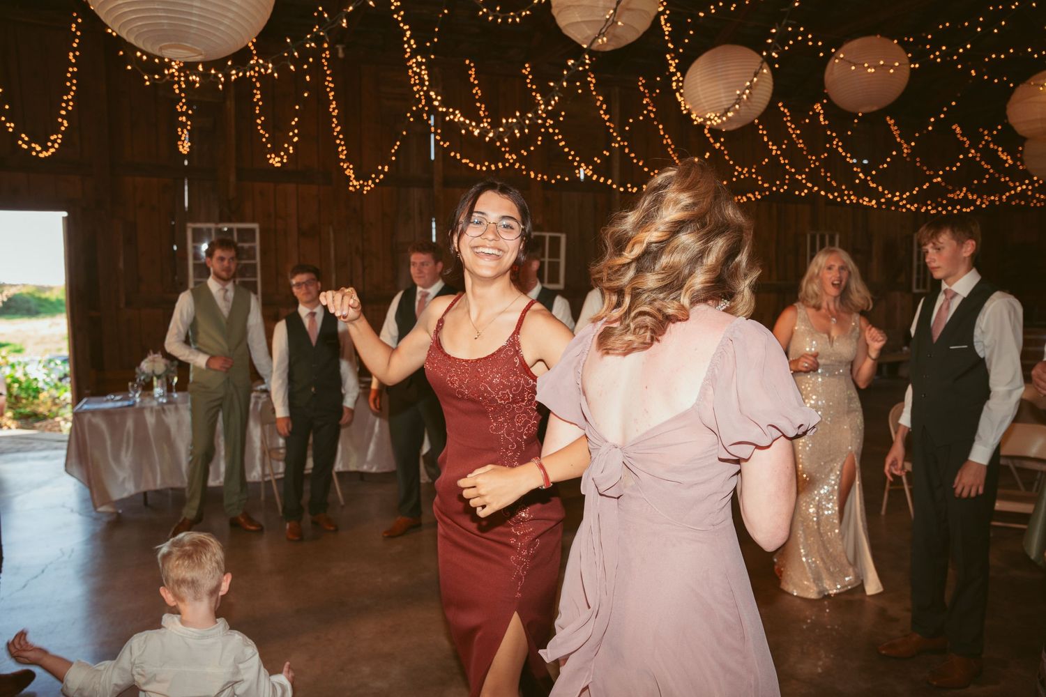 Wedding reception dance party with guests celebrating under warm lighting and decorative lanterns.
