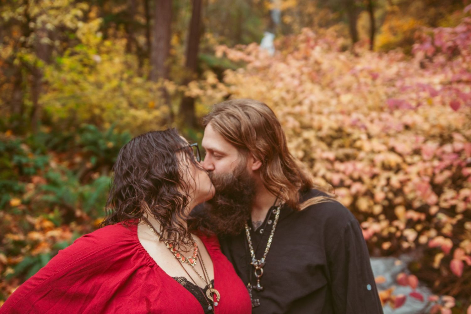 A romantic autumn photoshoot with a couple embracing among colorful fall trees.