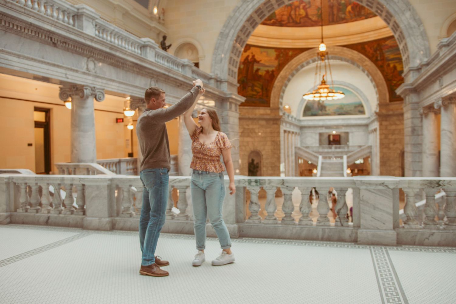 People dancing in an ornate marble hallway with classical architecture.