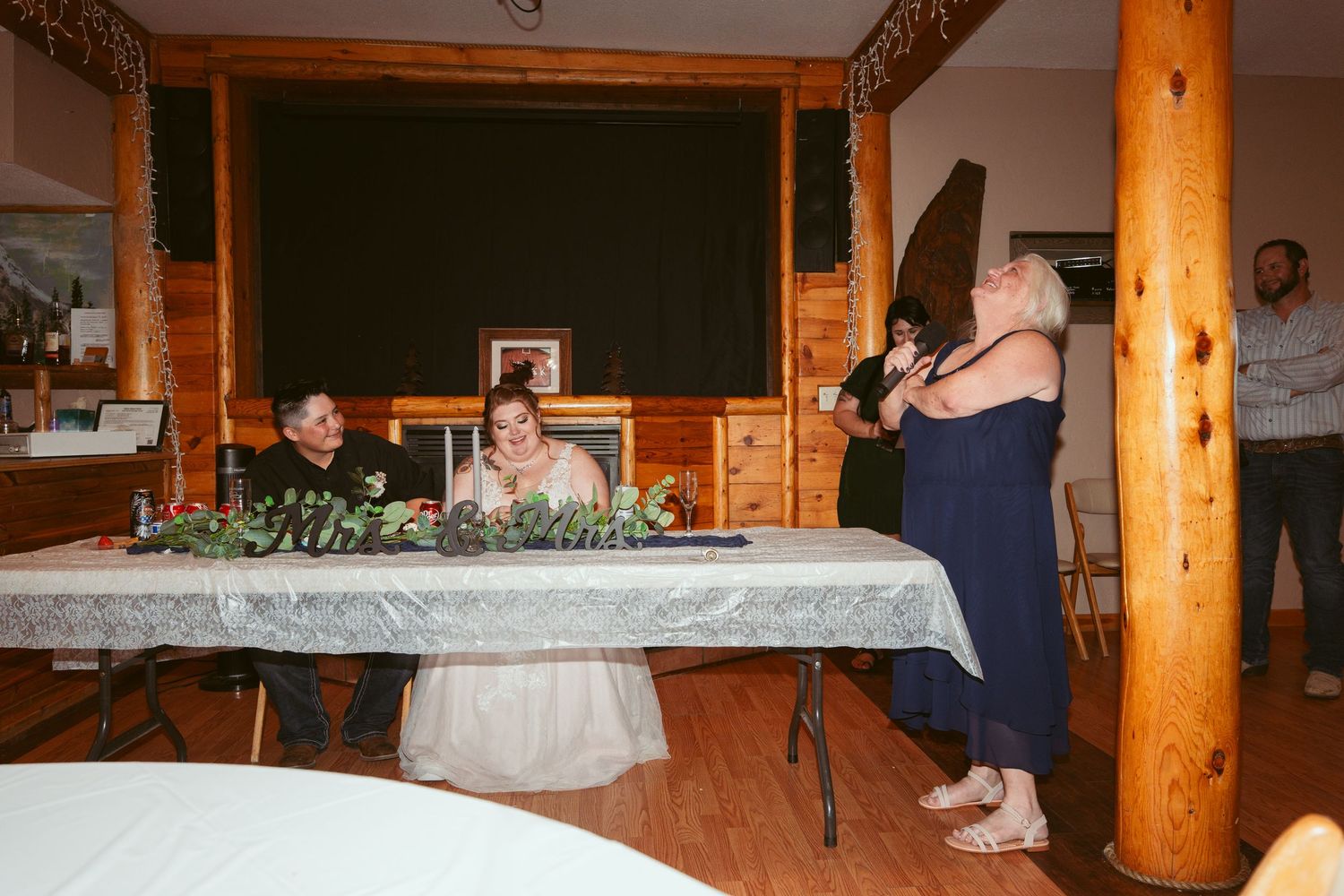 Wedding reception candid moment at head table with guests giving toasts.