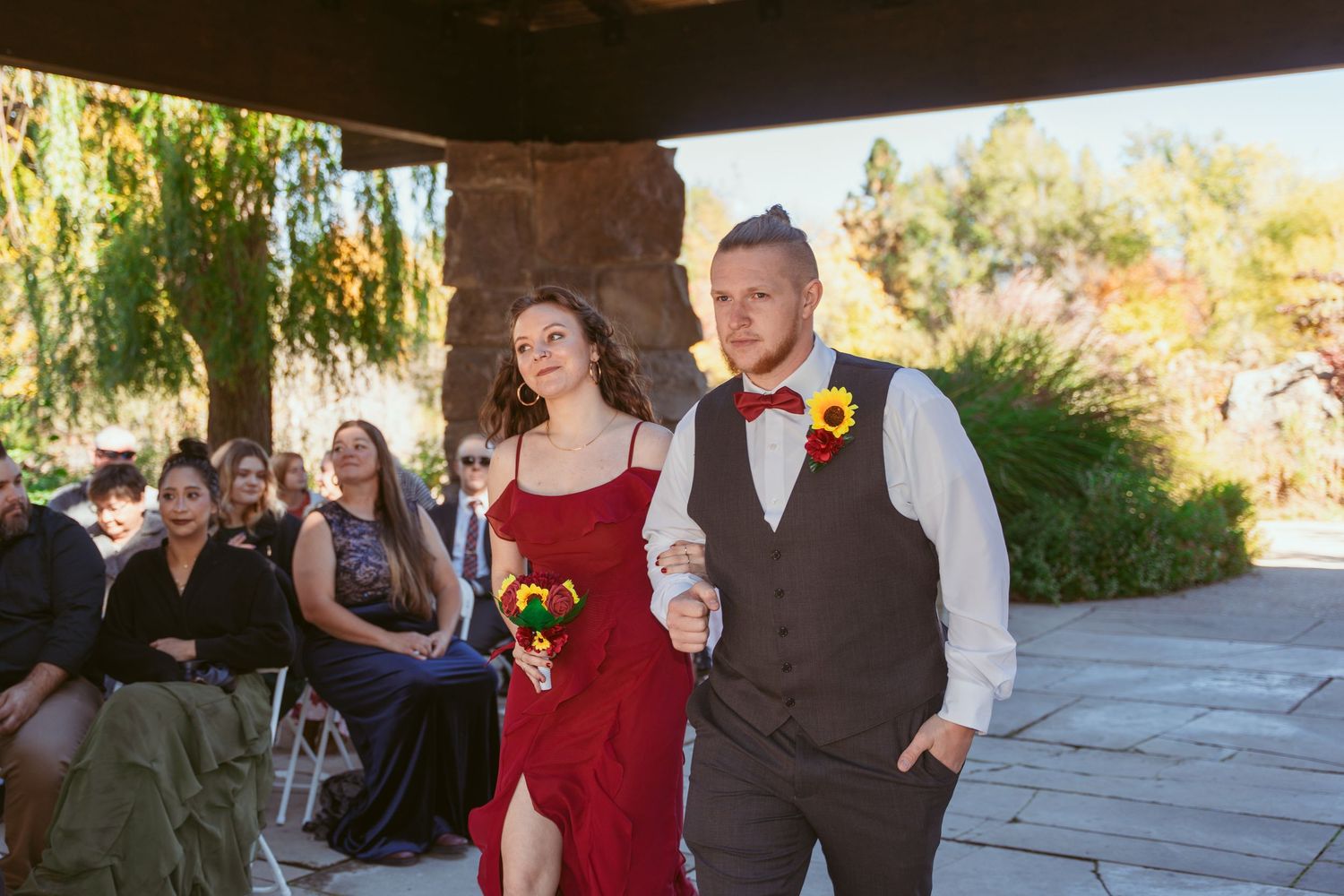 Guests socialize at an outdoor gathering under a covered stone patio.