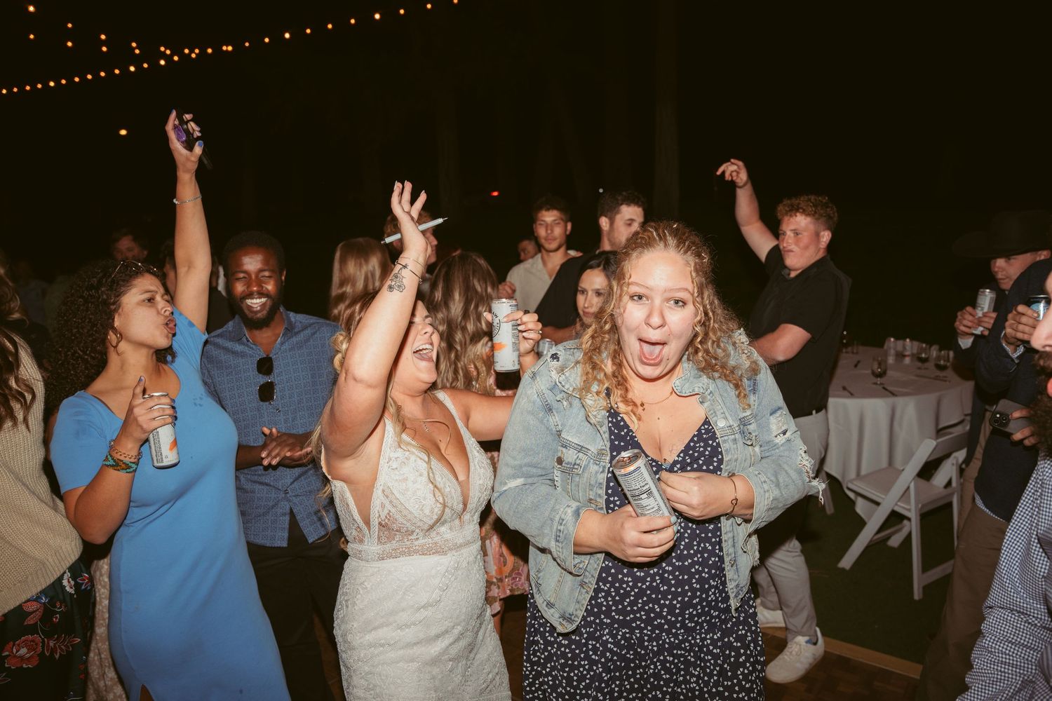 Enthusiastic dancers with raised arms enjoying themselves at a nighttime outdoor celebration.