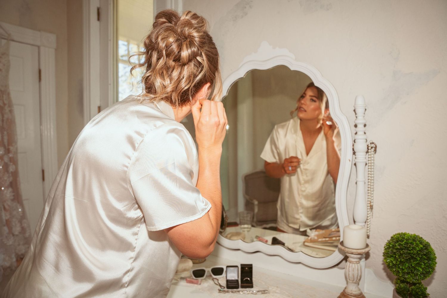 Person in white getting ready in front of a bathroom mirror and sink.